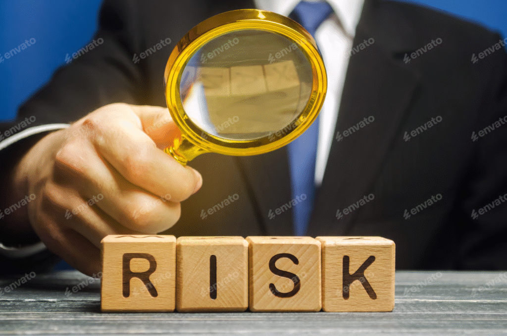 "Businessman holding a magnifying glass over wooden blocks spelling the word RISK."