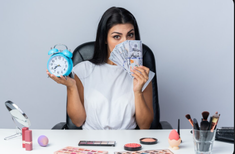 "Woman sitting at a table with makeup products, holding a clock in one hand and fanned-out dollar bills in the other."