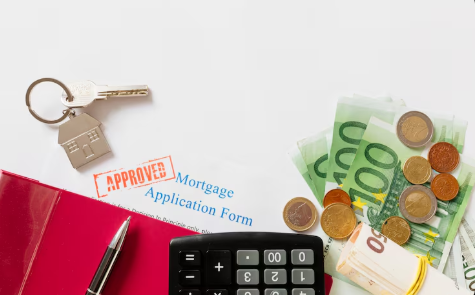 "Mortgage application form with an 'Approved' stamp, house keychain, calculator, pen, euro banknotes, and coins on a desk."