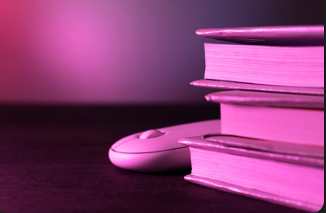 "Stack of books next to a computer mouse on a dark surface with pink lighting."