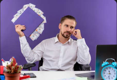 "Man sitting at desk holding a folder with dollar bills sticking out, looking thoughtful with a purple background."